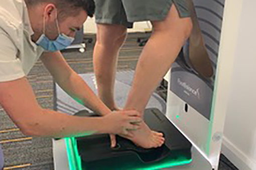 A Sports podiatrist lining up a foot on a sports podiatrist machine